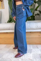 Pantalón de denim azul de calce relajado y fluido, decorado con pequeñas perlas aplicadas en toda la superficie con mayor densidad en el ruedo. Presenta pinzas frontales, bolsillos laterales y cierre de botón.