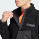 Buzo de tela fleece gruesa Adidas Terrex de color negro, con cuello alto, cierre frontal parcial con botones a presión, bolsillo frontal con solapa y el logo de Terrex en el pecho.