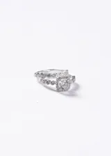 Set de dos anillos de plata 925. El primero es un anillo estilo Lady Di con una zirconia central cuadrada rodeada de pequeñas piedras y banda decorada. El segundo es un anillo tipo sin fin con engaste de pequeñas zirconias en toda la mitad superior.