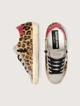 Zapatilla de cuero vacuno con pelo de potro y estampado animal print, combinada con gamuza en la puntera y lengüeta. Presenta una estrella lateral de cuero blanco, detalle de cuero rojo en el talón, cordones oscuros y suela con efecto envejecido.