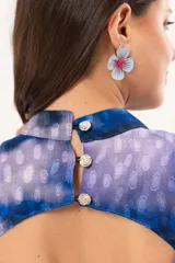 Vestido largo de manga larga con terminación campana, de color azul y violeta con estampado tie-dye, cuello mao con ojal y tajo frontal. Cuenta con flecos en el ruedo y tajo en la pierna.