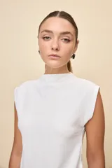 Top de calce entallado, sin mangas y con cuello alto, confeccionado en tejido texturado de líneas simples.