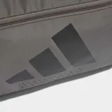 Bolso deportivo Adidas Training Defender, confeccionado en material ripstop resistente. Cuenta con un compartimento principal amplio con cierre de dos direcciones, correa para el hombro extraíble y acolchada, y perforaciones de ventilación cortadas a láser. Diseño en color gris con logo de la marca en negro.