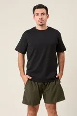 Bermuda deportiva color verde militar, de corte suelto, confeccionada en nylon. Cuenta con cintura elástica, cordón de ajuste, bolsillos laterales con cierre y detalle de líneas blancas en los costados.