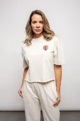 Remera de corte suelto y diseño cropped, con cuello redondo y mangas cortas con terminación desflecada. Presenta un pequeño parche estampado en el pecho con la imagen de la Estatua de la Libertad.