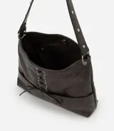 Cartera estilo hobo de cuero sintético color gris oscuro, con diseño de media luna y detalle de cordón cruzado con lazo regulable en el frente. Cuenta con bolsillos frontales funcionales, ojalillos metálicos y correa fija reforzada.