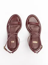Sandalias negras de cuero vacuno satinado con tiras finas en la capellada, pulsera cruzada al tobillo con hebilla metálica dorada y taco fino de 7,5 cm.