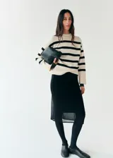 Chaleco oversize de punto con diseño a rayas horizontales en color crudo y negro, cuello redondo y mangas sisa con amplios ribetes elásticos.