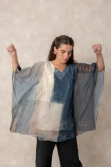 Blusa tipo túnica de gasa semitransparente con escote en V y mangas amplias. Presenta un diseño estampado con efecto acuarela en tonos azules, grises y marrones sobre fondo blanco.