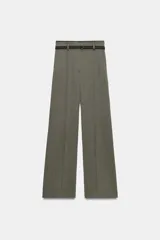 Pantalón de tiro alto con corte ancho y pernera recta. Presenta raya planchada en el delantero, bolsillos laterales y cierre frontal con cremallera y ganchos metálicos. Incluye un cinturón fino en tejido a contraste.