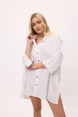 Vestido camisero negro de algodón, con mangas tres cuartos y cuello camisero. Presenta detalles de costura en zigzag color naranja en el cuello y en los puños.