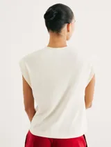 Camiseta sin mangas de tejido de punto fino, color gris claro, con cuello redondo y hombreras sutiles que aportan estructura.