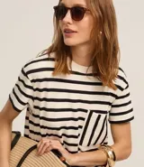 Vestido corto estilo camiseta de algodón, con cuello redondo, mangas cortas y bolsillo en el pecho. Presenta un patrón de rayas horizontales blancas y negras.