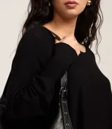 Suéter de tricot color negro con escote canoa, mangas murciélago y puños ajustados.