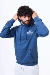 Buzo tipo canguro con capucha, confeccionado en felpa de algodón y poliéster. Presenta un diseño estampado en la espalda con tipografía y detalles gráficos.