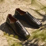 Zapatos de cuero negro con cordones laterales, suela de goma y punta cuadrada.