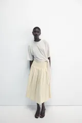 Falda midi de tiro medio ZARA Woman Collection confeccionada en hilatura con lino, con detalle de pliegues, bajo acabado en línea evasé y cierre lateral con cremallera oculta en costura.