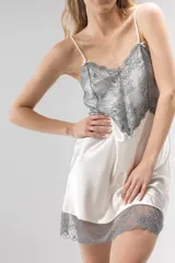 Camisón corto de satén color crema con detalles de puntilla gris en el escote y en el ruedo. Presenta breteles finos ajustables y un diseño fluido.