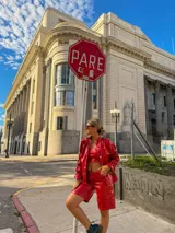 Camisa de cuero sintético color rojo, con cierre frontal de botones, cuello clásico y mangas largas con puños fruncidos y volados.