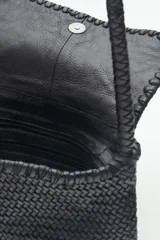 Cartera de cuero vacuno color tostado con diseño trenzado, acceso superior con cierre metálico, interior forrado con bolsillos.