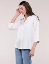 Camisa de satén azul marino con cuello mao, escote en V y mangas tres cuartos con hombro caído. Presenta silueta holgada, cierre frontal con botones y ruedo asimétrico.