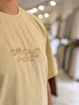 Remera oversize color beige con diseño bordado en el pecho con las palabras Off Court Game Set Match Duxon Team.