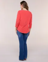 Remera blanca de algodón con elastano, de corte semi holgado, escote bote con ojalillos metálicos frontales, mangas tres cuartos raglán y ruedo asimétrico curvado.
