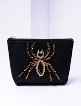 Estuche negro con cierre superior y aplique de araña con strass dorados y negros.