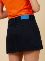 Minifalda de denim celeste con corte asimétrico y cierre con botón metálico.