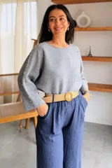 Sweater gris melange con detalles de perlas y strass aplicados en las mangas, de corte holgado y mangas largas.