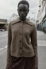 Chaqueta de punto color marrón con cuello de solapa desmontable en pelo sintético. Presenta cierre frontal con botones, manga larga y terminaciones en rib.