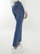 Pantalón jean azul de corte recto, con terminación desflecada y botones dorados en el ruedo.
