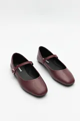 Balerinas color crudo de símil cuero texturizado, con punta redondeada, tira sobre el empeine y hebilla metálica ajustable.