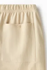 Pantalón en punto de mezcla de algodón, color beige, de corte regular y piernas rectas. Cuenta con cintura elástica con cordón ajustable, bolsillos laterales al bies y bolsillos traseros de parche.
