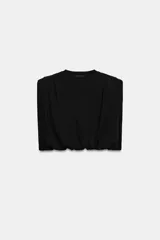 Top de algodón con cuello redondo, diseño sin mangas con hombreras marcadas y detalle de pliegues. Presenta un bajo acabado tipo globo con elástico.