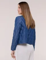 Campera corta azul de lyocell con acabado matelaseado en patrón de ondas, escote redondo, cierre frontal con cremallera y manga larga.