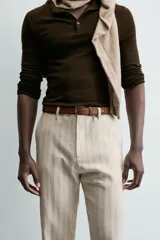 Cinturón de piel color marrón con costuras decorativas en los bordes. Presenta una hebilla metálica rectangular de color plateado y un pasador a juego.