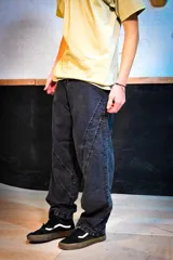 Jean baggy gris con efecto gastado, tiro alto, corte ancho de piernas y costuras decorativas diagonales en el frente.