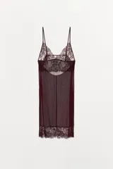 Vestido corto color vino tinto, con tirantes finos ajustables y escote en pico. Presenta un panel de encaje floral en el busto y un borde de encaje en el ruedo. El cuerpo principal es de tejido ligero y semitransparente.