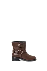 Botas cortas de ecocuero color chocolate, con base de 1,5 cm, taco de 2,5 cm y caña de 21 cm de alto. Presentan dos correas con hebillas y un arnés con argolla metálica.
