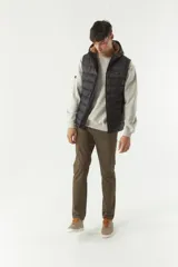 Chaleco negro acolchado con capucha ajustable, cierre frontal y bolsillos laterales con cierre. Logo de la marca en el pecho. Colección Otoño Invierno 2025. El modelo usa talle M. Composición 100% nylon.