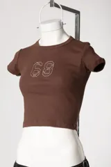 Baby tee de calce al cuerpo y manga corta, con cuello redondo y diseño con tachas frontales.