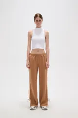 Pantalon deportivo de corte recto y tiro medio, color beige oscuro. Presenta una banda lateral en tono crema y aberturas ajustables con cordones en los tobillos. Cuenta con cintura elástica.