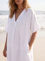 Vestido estilo túnica color fucsia de lino, con escote en V, manga corta, bolsillos laterales y diseño asimétrico más largo en la parte trasera.