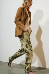 Pantalón jeans ZW Collection de tiro medio y corte balloon, confeccionado en algodón con diseño estampado de flores en tonos oscuros sobre base beige. Cuenta con cinco bolsillos, trabillas para cinto y cierre frontal con cremallera y botón metálico.