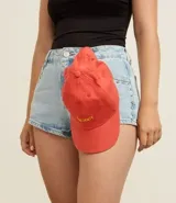 Gorra de sarga de algodón color coral o salmón con visera curva y bordado frontal en hilo amarillo con la palabra "Caliente".