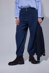 Pantalón tipo bombachita con pinzas que aportan volumen, confeccionado en Tencel. Presenta cierre frontal con botones dorados, bolsillos delanteros y ruedo ajustable mediante botón dorado.