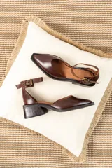 Zapatos de cuero color chocolate con diseño de punta cuadrada, taco bloque bajo y tira ajustable al tobillo con hebilla metálica.
