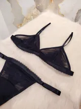Conjunto de lencería compuesto por un corpiño triangular de microtul transparente con detalles de encaje en las copas y una tanga regulable de elástico ancho.