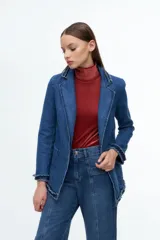 Blazer de denim azul con solapas y puños decorados con volados desflecados. Presenta un corte estructurado con bolsillos laterales y cierre frontal.
